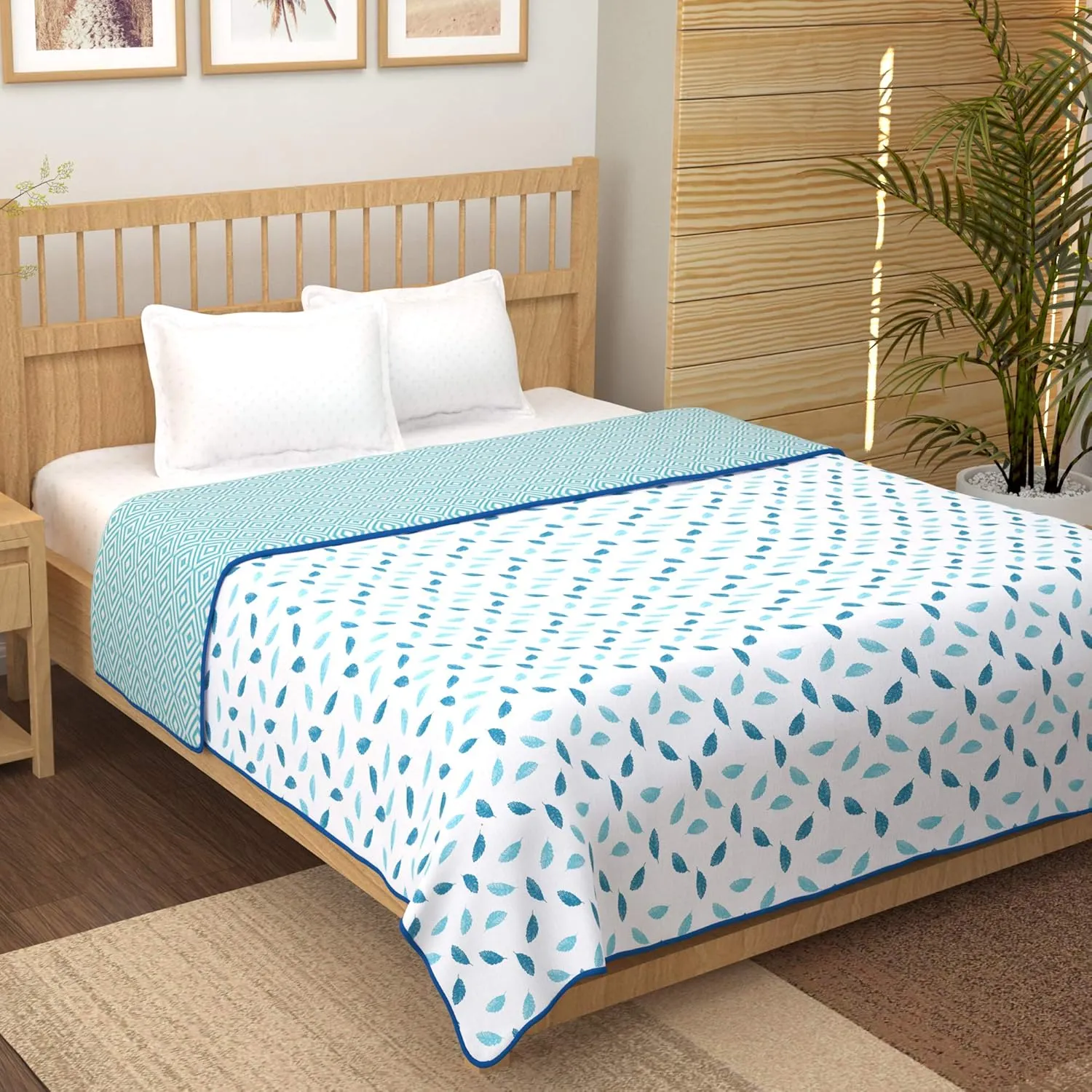 Dusty blue floral printed cotton bedsheet laid flat with two pillow covers on a styled bed in soft daylight.