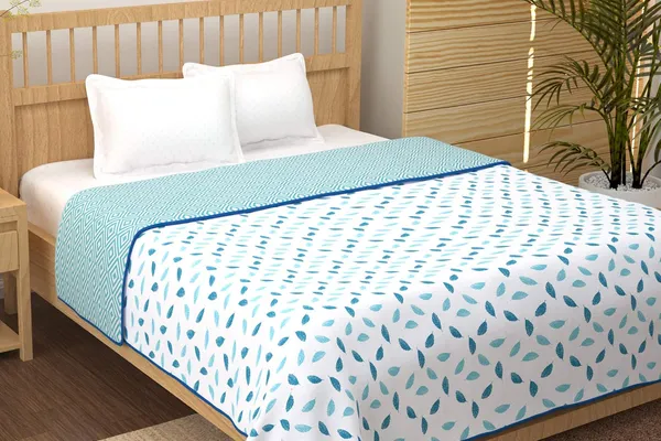 Dusty blue floral printed cotton bedsheet laid flat with two pillow covers on a styled bed in soft daylight.